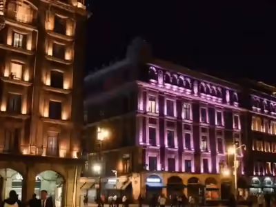 Fachada iluminada en tonos rosa y morado para un evento