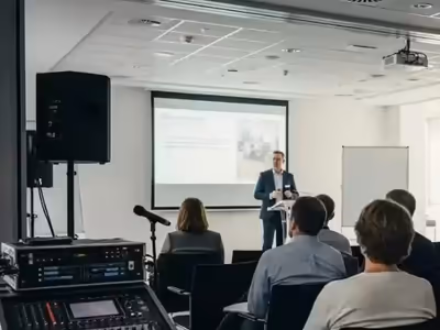 Mezcladora y micrófono montados al pie del escenario de una ponencia