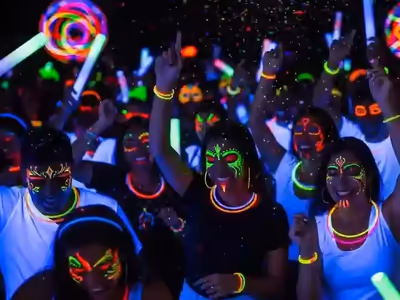 Invitados con pintura fluorescente y pulseras glow brillando bajo luz negra