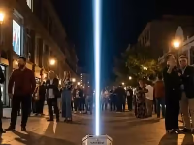 Haz vertical de sky tracker visible desde la calle con gente mirándolo